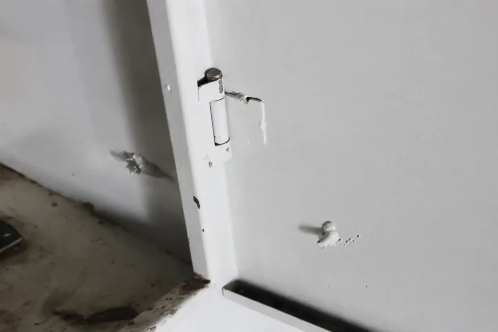 Coating wear around a welded electrical cabinet door hinge